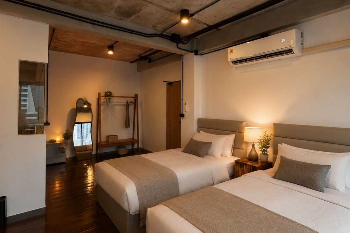 Habitación de hotel con dos camas, un espejo grande y un equipo de aire acondicionado.