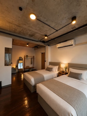 Habitación de hotel con dos camas, un espejo grande y un equipo de aire acondicionado.