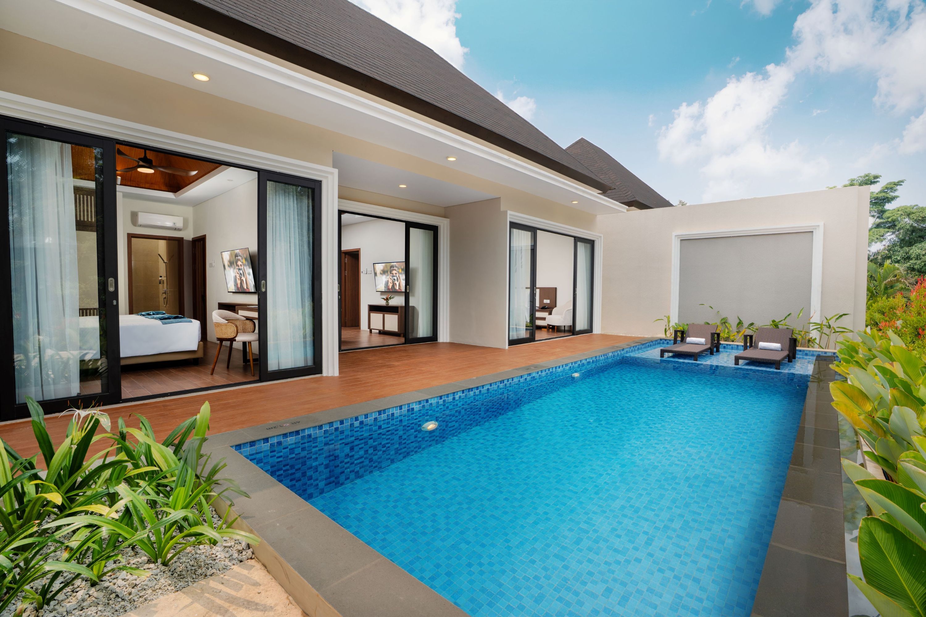 Il s’agit d’une r ésidence moderne dotée d’une piscine, de portes-fenêtres coulissantes donnant accès à une chambre et d’un patio aménagé avec des chaises longues.