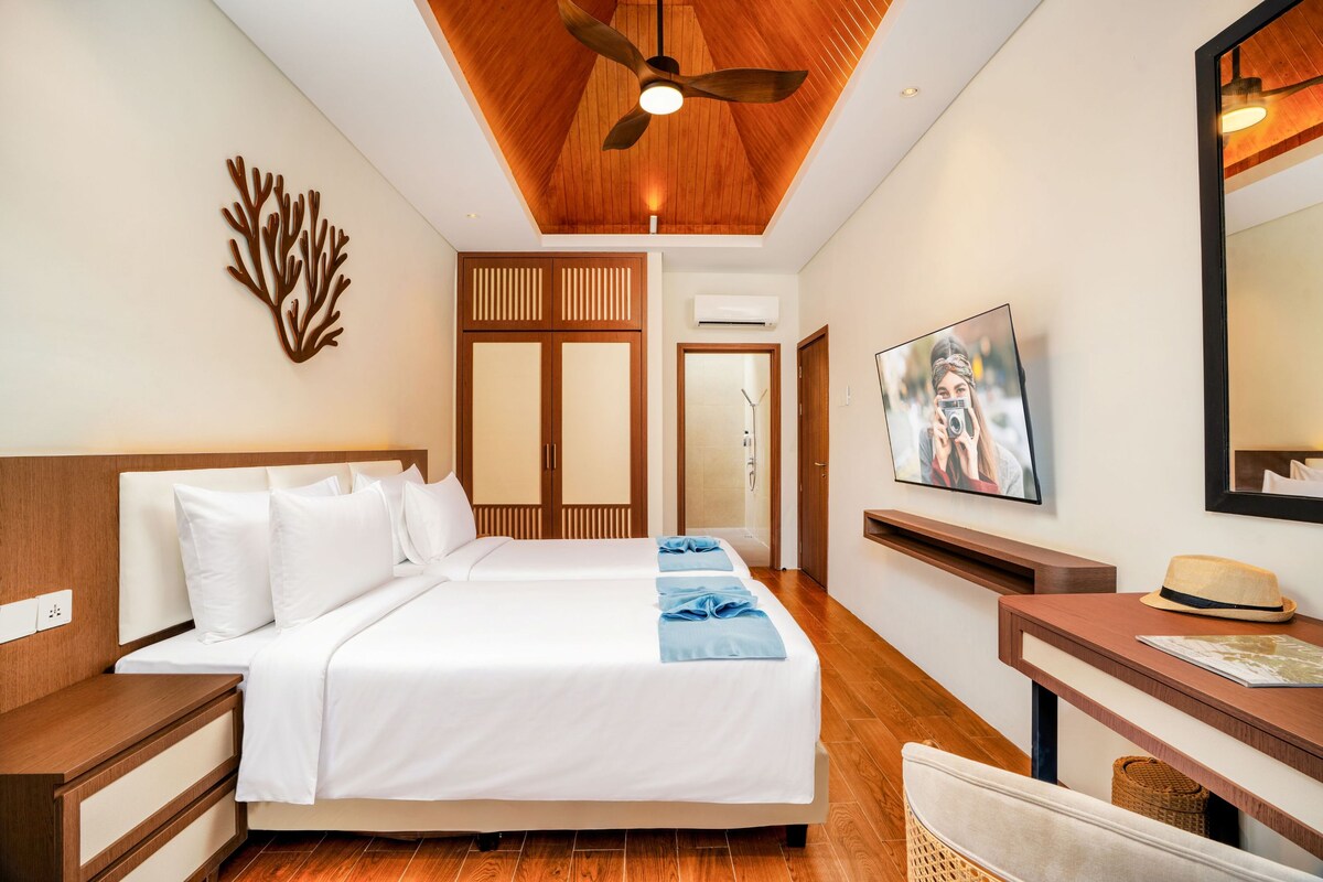 A hotel room with a bed, a desk, a television, and a ceiling fan.