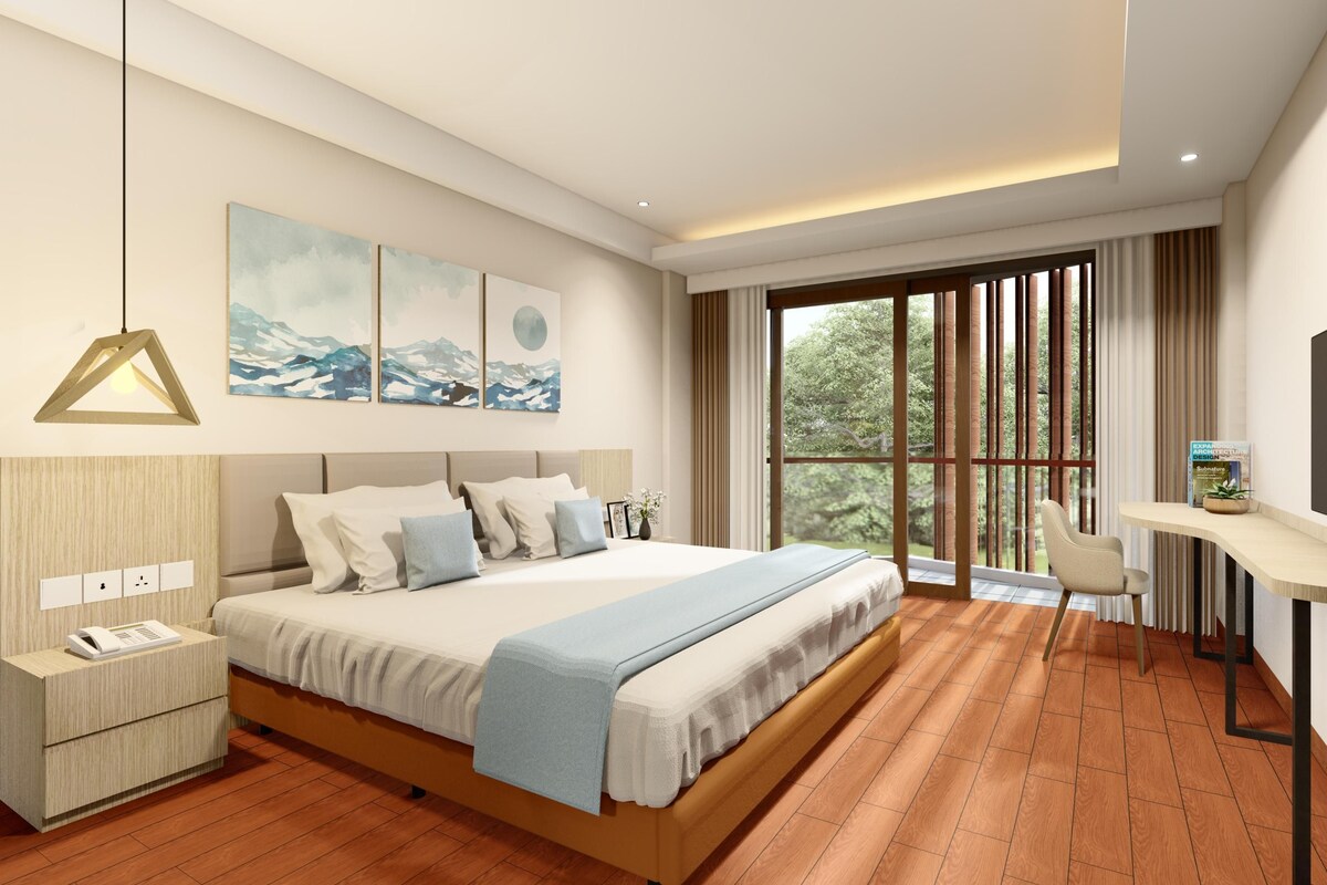 A modern bedroom with a large bed, bedside tables, a desk with a chair, a TV, and a large window with a view of greenery.