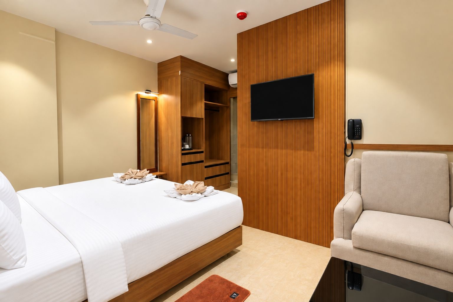 Quarto de hotel com cama, cadeira, televisão e telefone.
