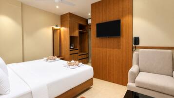 Quarto de hotel com cama, cadeira, televisão e telefone.