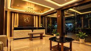 Ein Hotel-Empfangsbereich mit einem Marmor-Empfangstresen, einer Bank und einer Chandelier.