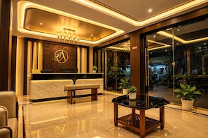 A hotel reception area with a marble reception desk, a bench, and a chandelier. - Ambika Residency (Sri Vijaya Puram)