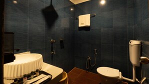 Ein Badezimmer mit dunkelblauen Fliesen, einem weißen Waschbecken, einer Toilette und einer Dusche.