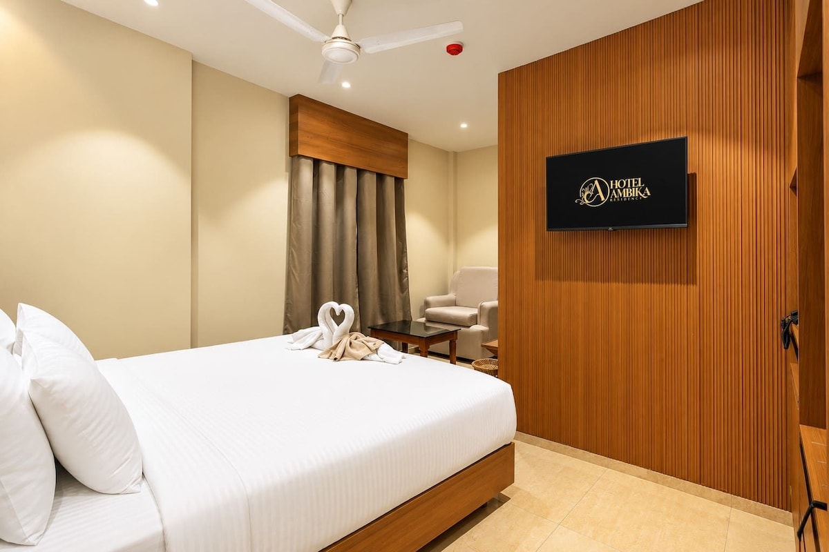 Ein Hotelzimmer mit Bett, Wandfernseher, Deckenventilator und einer Wand aus Holzpaneelen.