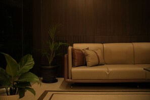 A room with a sofa and a potted plant.
