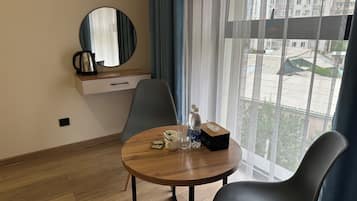 A hotel room with a round wooden table, two chairs, a coffee maker, a bottle of water, and a tissue box.