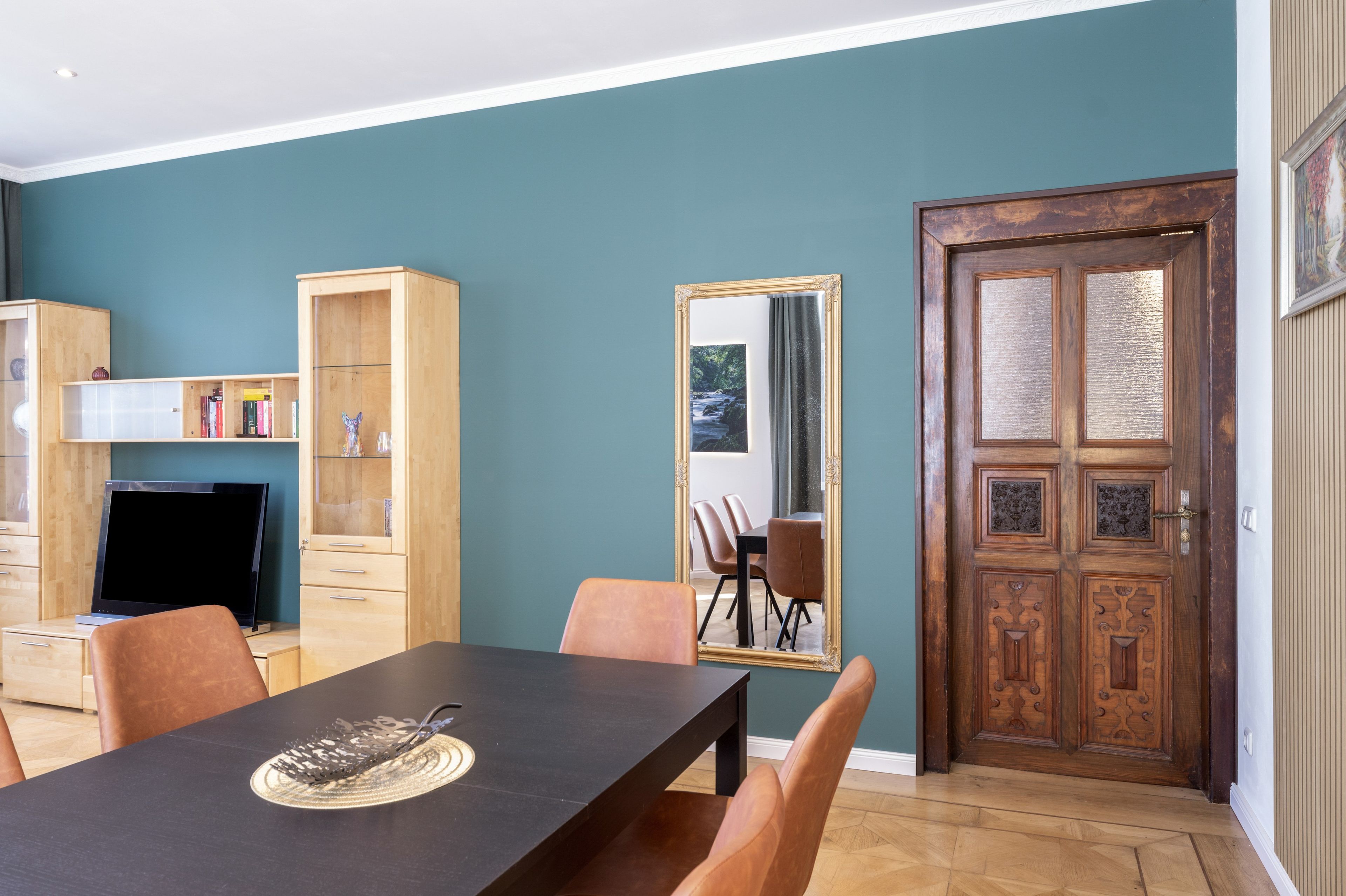 Ein Essbereich mit Tisch, Stühlen, einem Holzschrank und einem Spiegel.