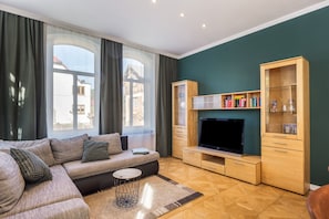 A living room with a sofa, a coffee table, a TV, and wooden cabinets.