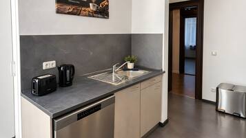 A modern kitchen with a built-in dishwasher, a coffee maker, and a toaster.