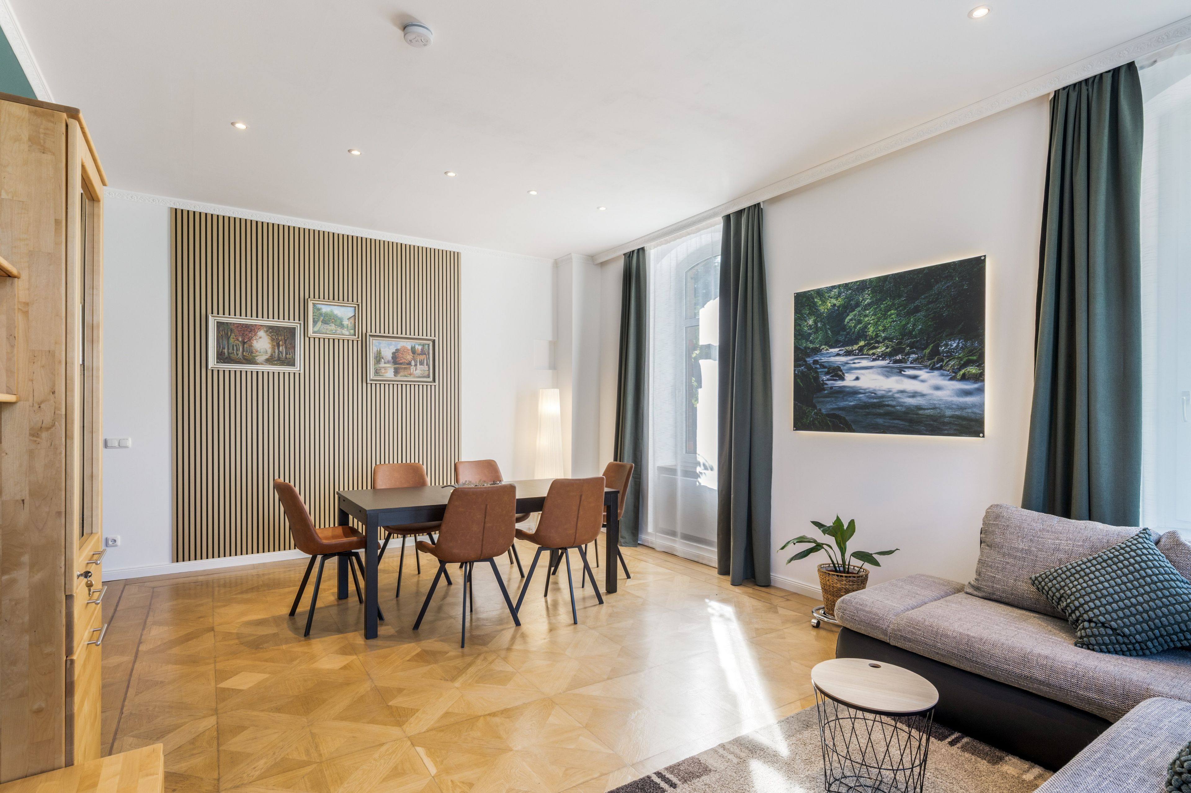 A modern living room with a dining area, a sofa, a coffee table, and a large window with curtains.