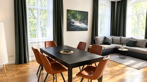 Ein modernes Wohnzimmer mit Essbereich, großen Fenstern und einem Gemälde an der Wand.