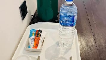 Una bandeja con dos tazones blancos, dos cucharas, una botella de agua y un recipiente pequeño con alimentos.