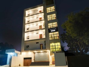 A multi-story building with illuminated windows and a sign indicating 'TOWNHOUSE.' - Super Townhouse Pahadiya (Varanasi)