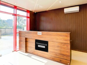 A reception desk with a 'Townhouse' sign, a reception area with a wooden panel wall, and a large window. - Super Townhouse Pahadiya (Varanasi)