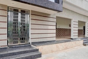 A building entrance with a metal gate, steps leading up to a landing, and a tiled wall with a geometric pattern. - Hotel O Yamuna Riverview Swyamwar Resort (Mathura)