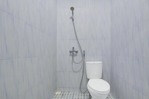 A small bathroom with a toilet, a shower, and tiled walls. - Spacious Triple Suite for Groups With Free Wifi (Yogyakarta)