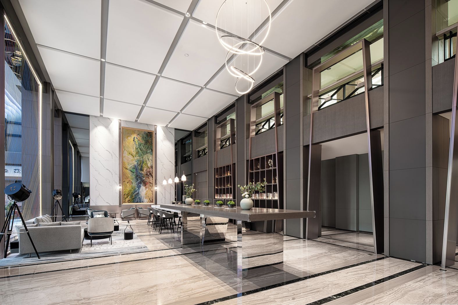 A spacious lobby with a long reception desk, seating area, and a large abstract painting on the wall.