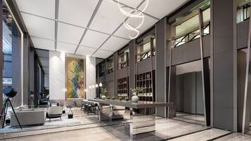 A spacious lobby with a long reception desk, seating area, and a large abstract painting on the wall.