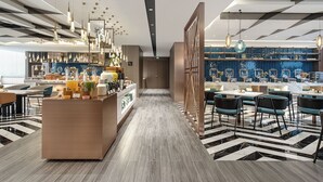 Eine moderne Hotelhalle mit einer zentralen Bar, Sitzgelegenheiten und einem strukturierten Boden.