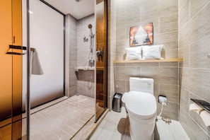 Et moderne badeværelse med brusekabine i glas, toilet og vask.