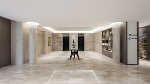 Un vestíbulo de hotel moderno con piso de mármol, una mesa redonda central y un mostrador de recepción.