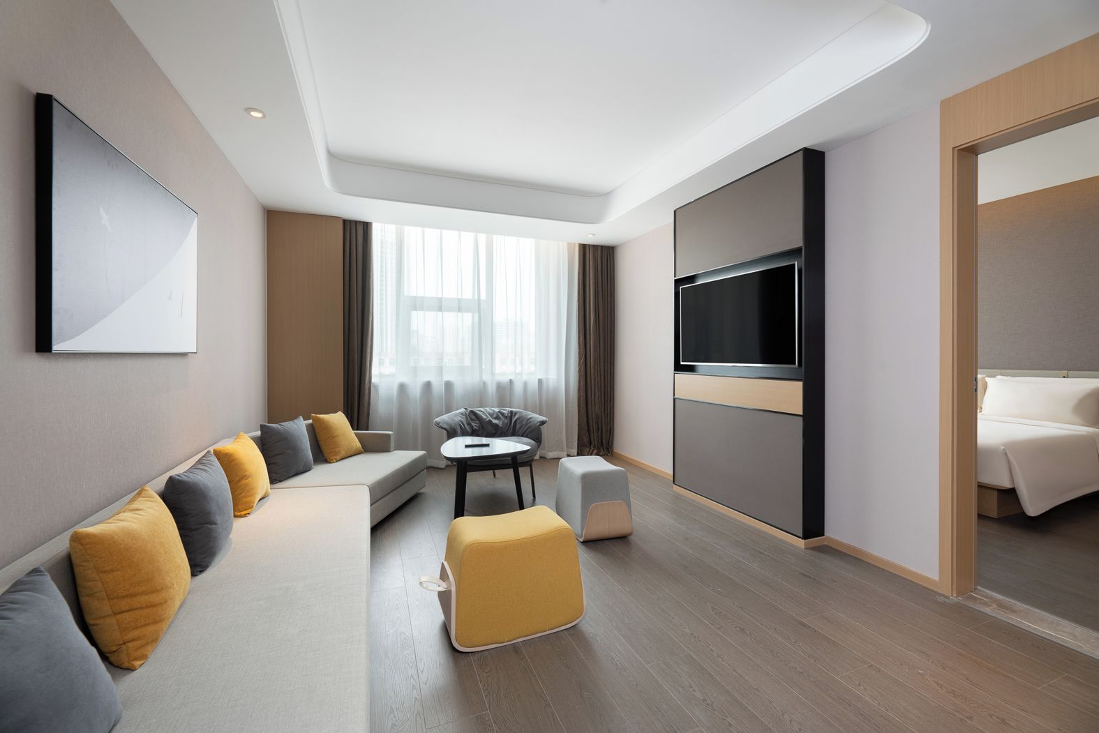 Habitación de hotel moderna con sofá, reposapiés, televisor de pantalla plana y cama.