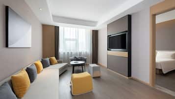 Habitación de hotel moderna con sofá, reposapiés, televisor de pantalla plana y cama.