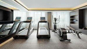 Ein moderner Fitnessraum mit Laufbändern, Crosstrainern und einer Trainingsbank.