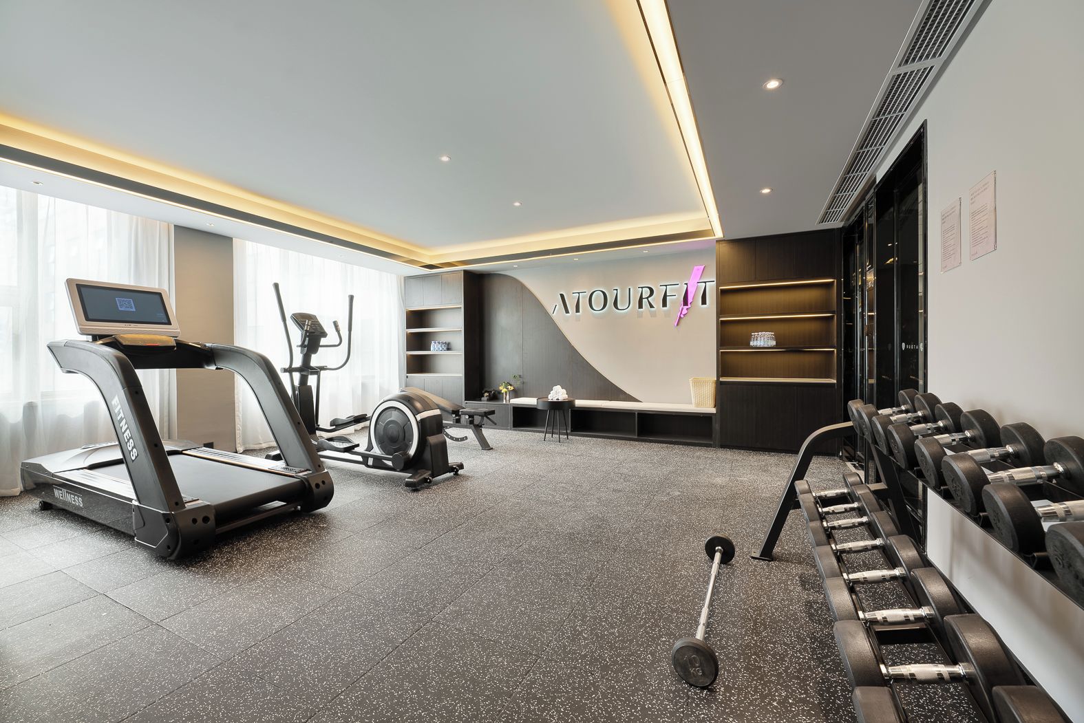Une salle de sport moderne équipée de tapis de course, de vélos elliptiques et de poids libres.