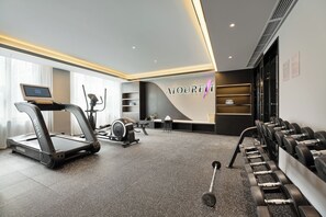 A modern gym with treadmills, elliptical machines, and free weights.