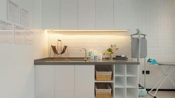 Una cocina moderna con lavadora integrada, sala de lavandería autoservicio y estación de planchado.