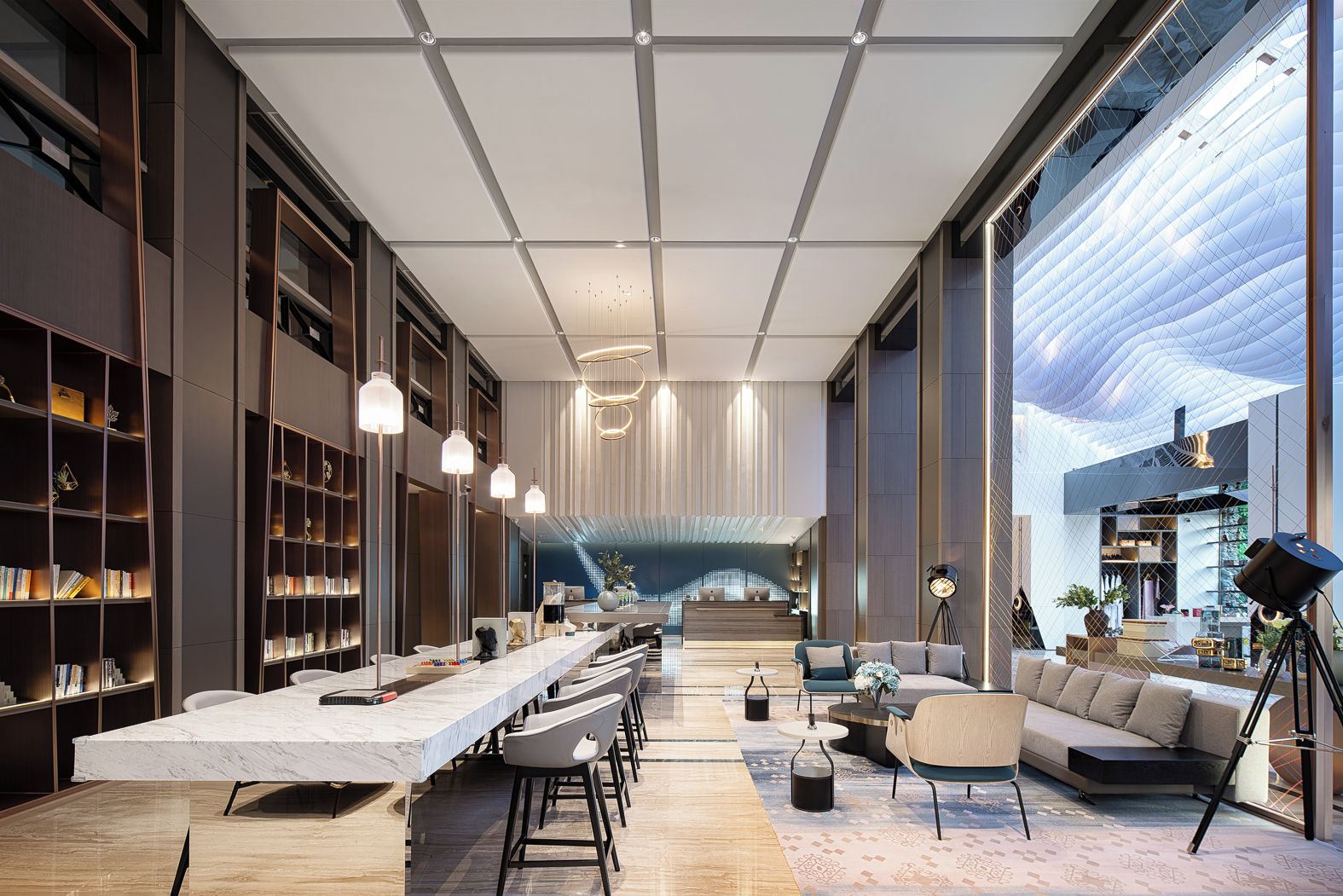 A modern interior with a long reception desk, seating area, and bookshelves.