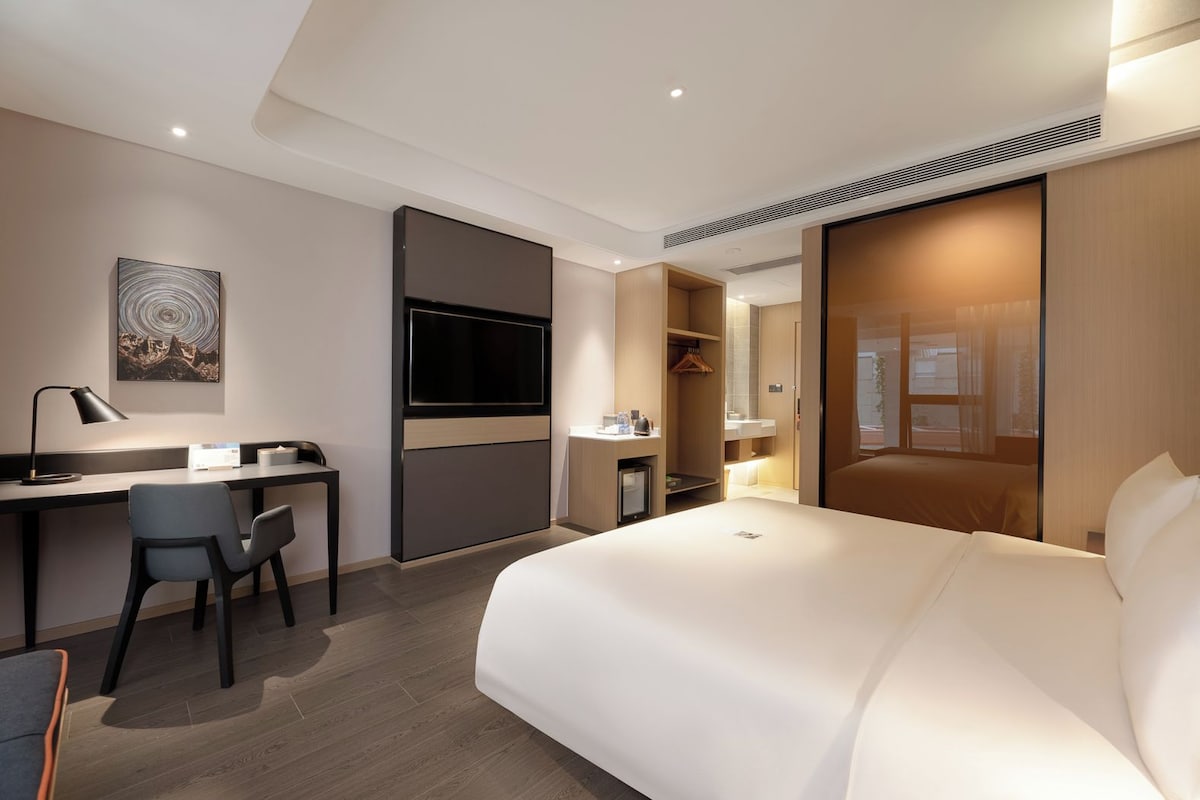 Et moderne hotelværelse med seng, skrivebord, stol og fjernsyn.