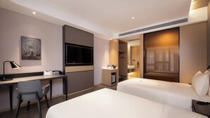 Ein Hotelzimmer mit Schreibtisch, zwei Betten, Fernseher und einem Bild an der Wand.