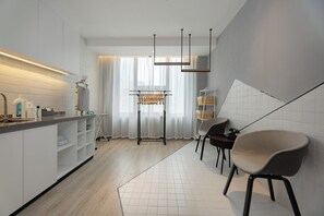 A modern kitchen with a built-in oven, a dining area with chairs, and a large window with curtains.