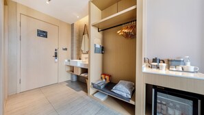 A modern hotel room with a built-in wardrobe, a small kitchenette, a seating area with a mirror, and a mini fridge. - Atour Hotel Dalian Xinghai Square (Dalian)