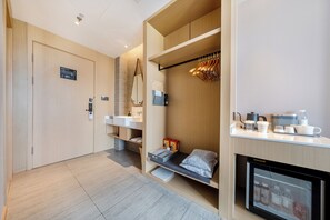 A modern hotel room with a built-in wardrobe, a small kitchenette, a seating area with a mirror, and a mini fridge. - Atour Hotel Dalian Xinghai Square (Dalian)