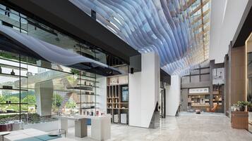 A spacious lobby with a high ceiling, modern furniture, and a view of the outdoors.