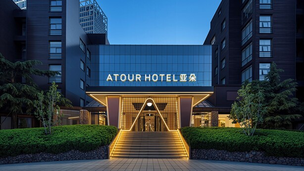 Das Atour Hotel mit moderner Fassade, einem markanten Eingangsbereich mit Treppe und blauem Himmel.