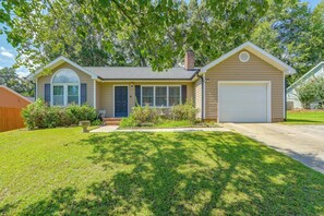 A single-story house with a front garage, a covered porch, and a well-maintained lawn. - Large Wooded Yard, 7 Mi to Truliant Amphitheater (Charlotte)