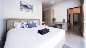 Een moderne slaapkamer met een groot bed, een nachtkastje, een bureau en een kledingkast.