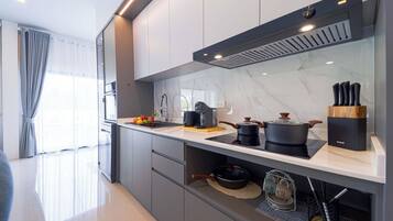 A modern kitchen with a built-in oven, a coffee machine, and a range hood.
