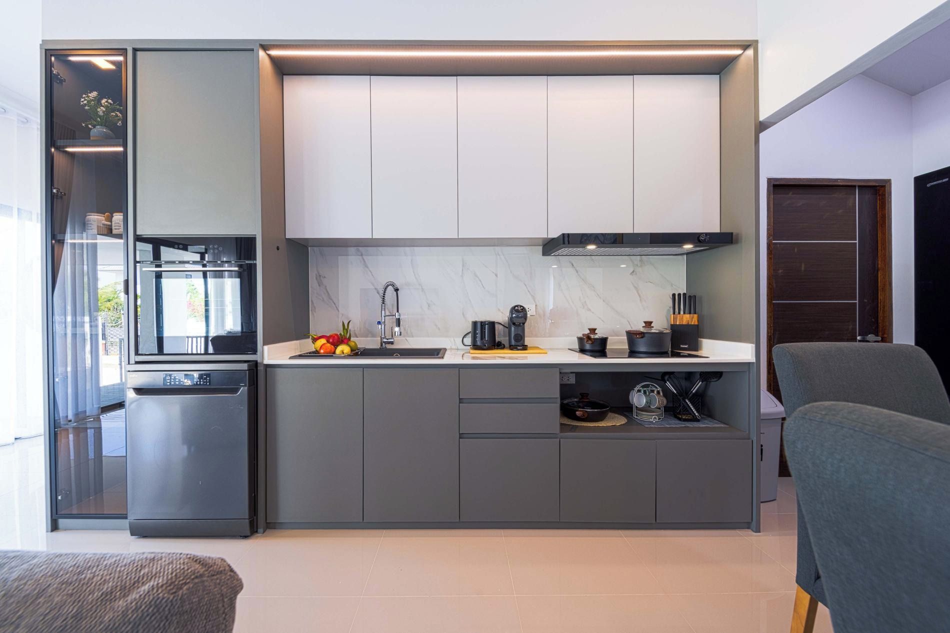 Una cocina moderna con horno integrado, cafetera y frutero sobre la encimera.