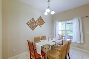 A dining area with a glass table, woven chairs, and a window with curtains. - Resort Pool, Lanai! Family Retreat Near Disney (Kissimmee)