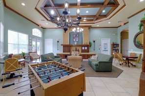 A spacious living room with a foosball table, comfortable seating, a fireplace, and a chandelier. - Resort Pool, Lanai! Family Retreat Near Disney (Kissimmee)