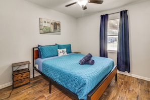 A bedroom with a bed, a nightstand, a ceiling fan, a window with curtains, and a wall-mounted picture. - Walk to AT&T Stadium! Massage Chair & Cowboy Pool (Arlington)