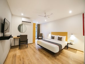 A hotel room with a bed, desk, chair, and a television. - Townhouse Near Appu Ghar (Gurugram)